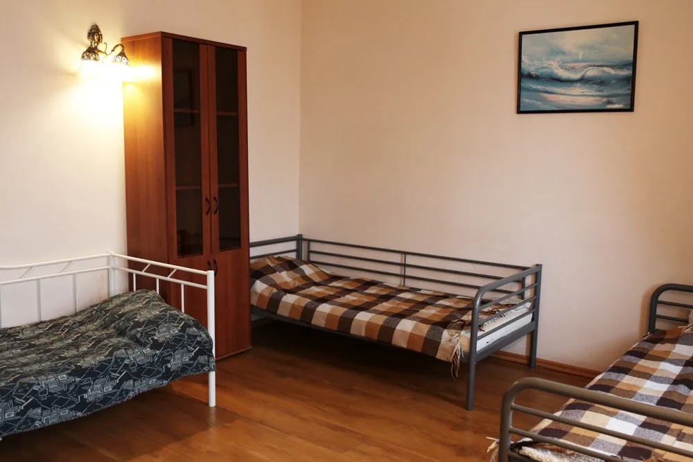 Комната с кроватями, шкафом и картиной, окно во двор